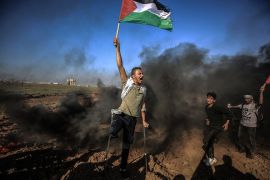 معاق فلسطيني يرفع علم فلسطين خلال مظاهرات العودة على حدود قطاع غزة