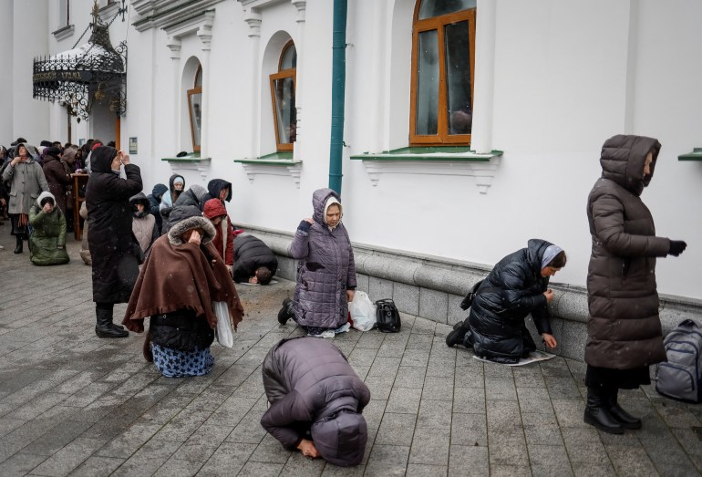 Believers pray outside a church during a service at a compound of the Kyiv Pechersk Lavra monastery in Kyiv